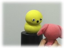 photo: Keepon looking at a toy in a person's hand