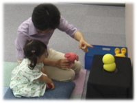 photo: A 2-year-old girl looking at Keepon with her mother