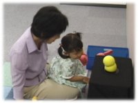 photo: A 2-year-old girl closely looking into Keepon