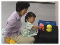 photo: A 2-year-old girl showing a toy to Keepon