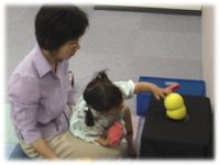 photo: A 2-year-old girl touching Keepon's head