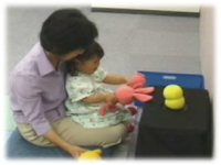 photo: A 2-year-old girl playing with Keepon using a toy