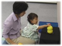 photo: A 2-year-old girl stroking Keepon's head with praise